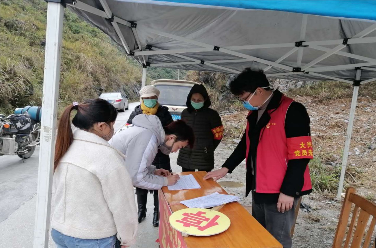 蓝振榕在弄模村口疫情防控监督岗检查来往行人 摄影/蒙玉作蓝振榕冒雨